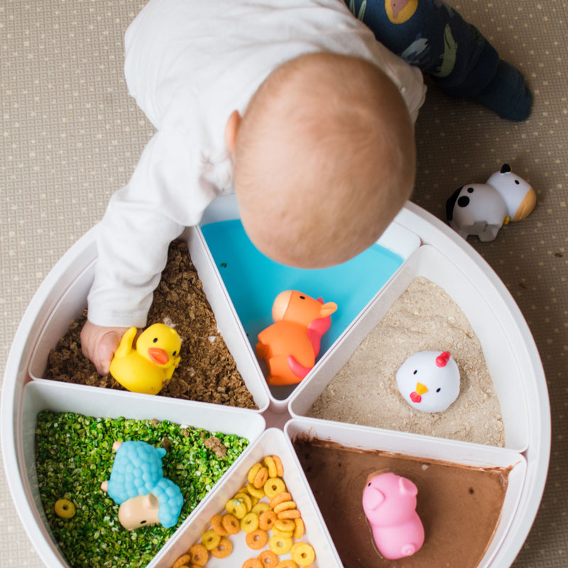 Baby playing with farm animals in a sensory bin