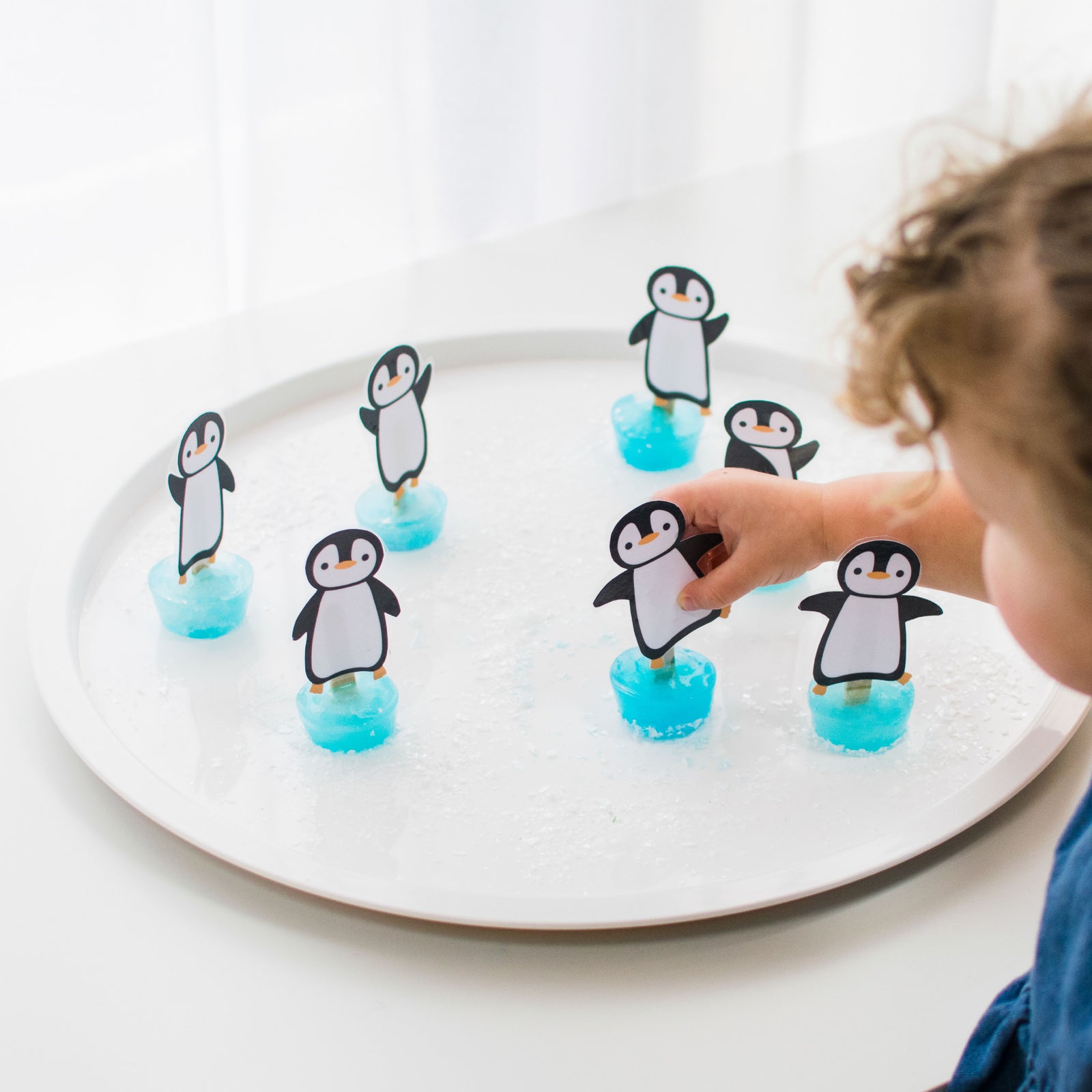 Child playing with and printed penguins on PlayTRAY lid