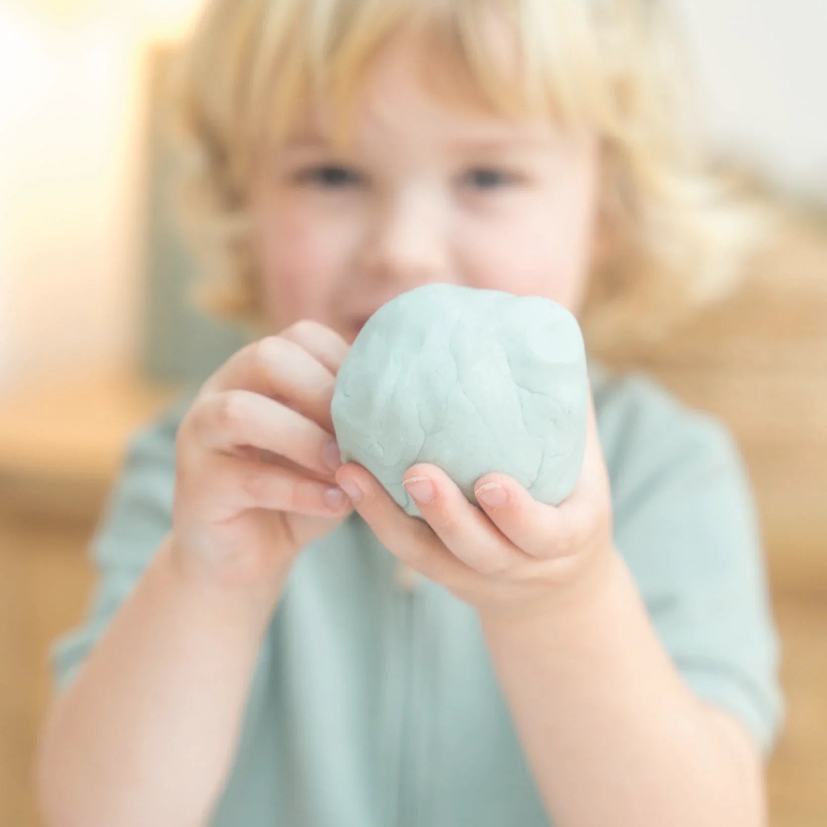 Child holding green playdough