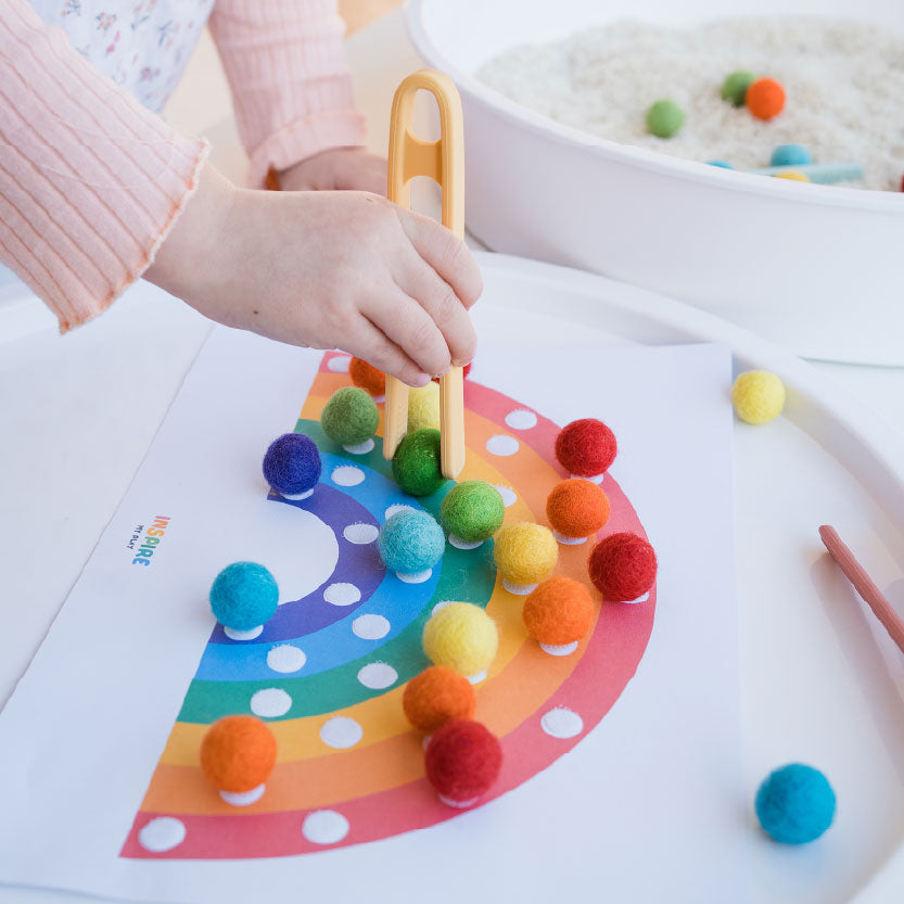 Rainbow and felt balls Childs hand with tongs