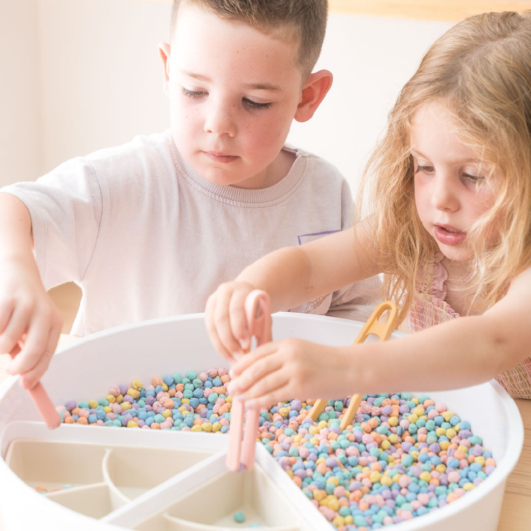 Two children playing with coloured chickpeas