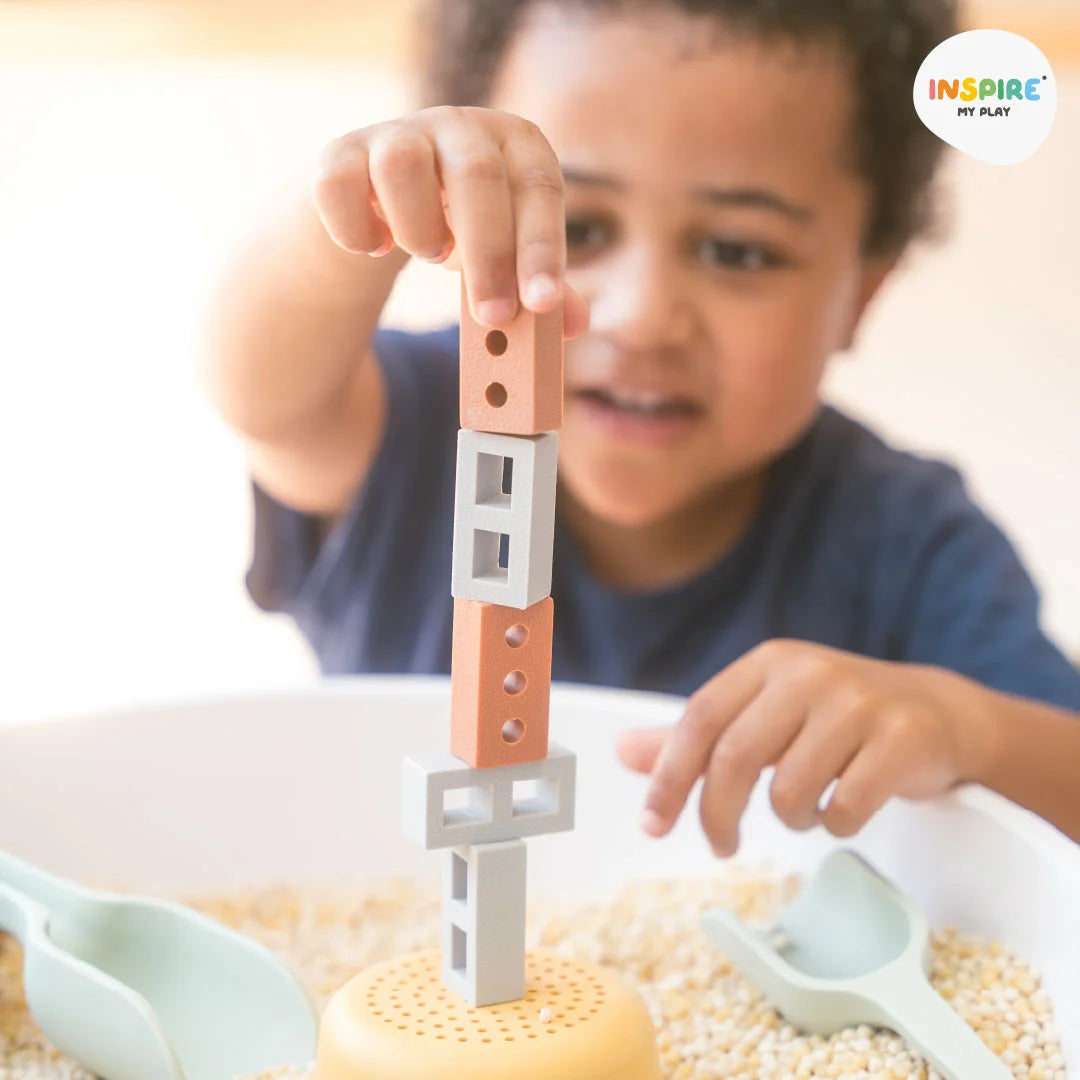 Young child building a tower with bricks and blocks during sensory play using the PlayTRAY