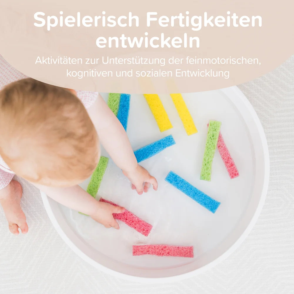 Baby playing with colourful foam strips in a play tray.