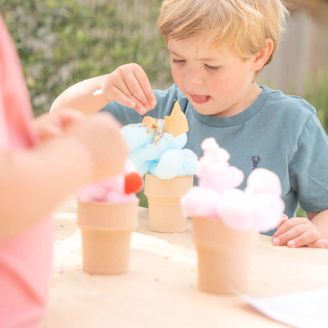 Child playing with silicone ice cream set filled with shaving foam, topped with sprinkles and a wafer. 