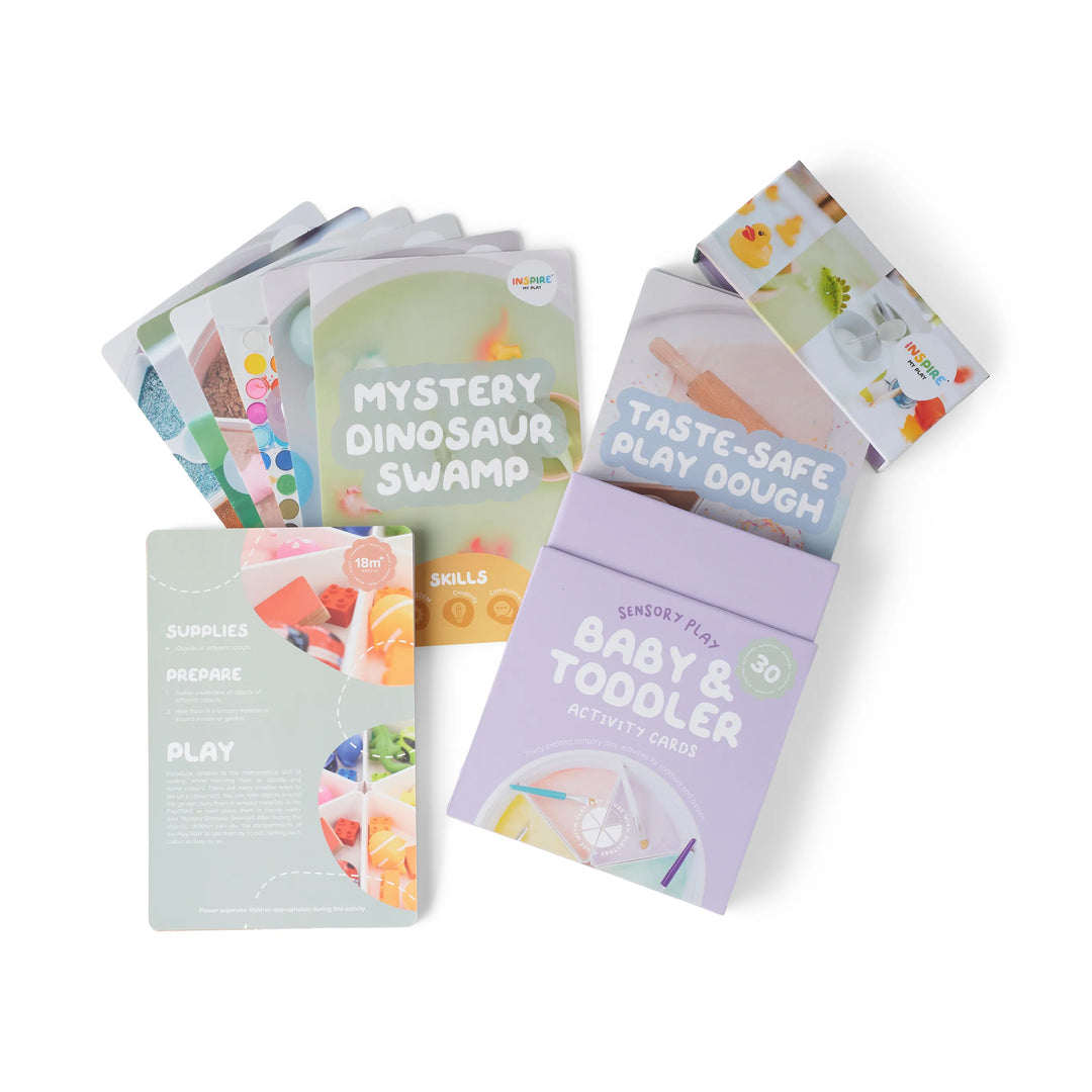 A set of 30 baby and toddler sensory play activity cards in a cardboard box. Visible titles include 'Mystery Dinosaur Swamp,' and 'Taste-Safe Play Dough.'