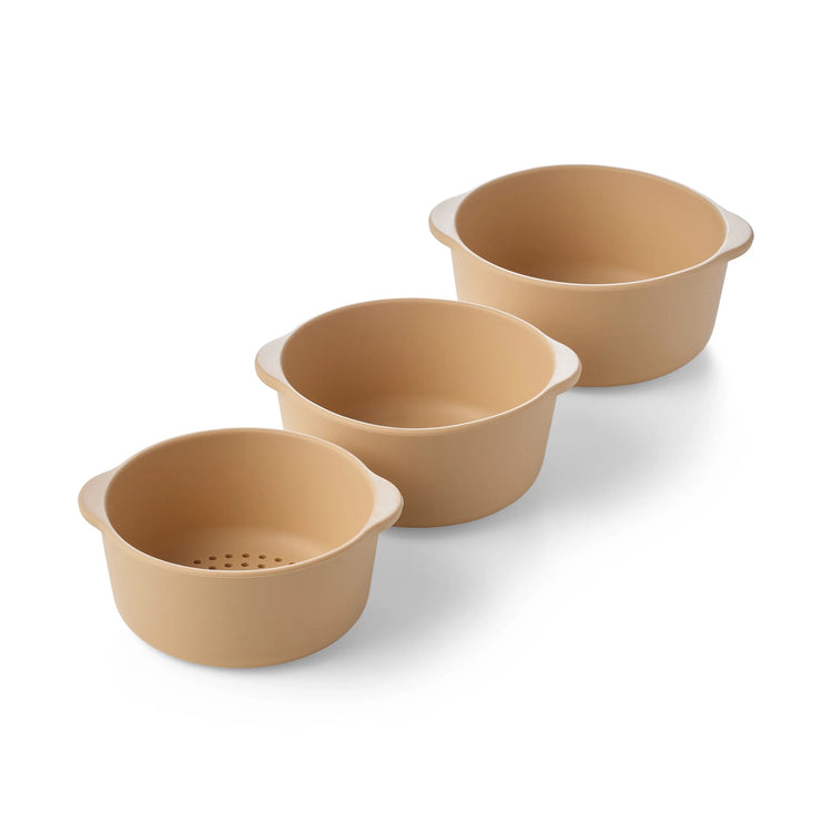 Three round beige silicone sensory play nesting bowls for children including one sieve bowl arranged diagonally on a white background.