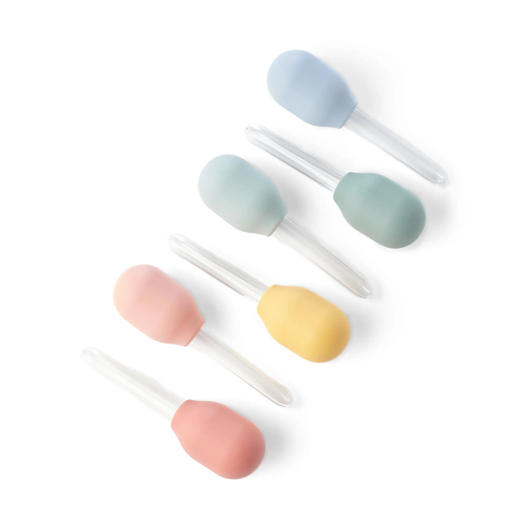 Five pastel silicone droppers/pipettes for children's sensory play, water play and STEM play in pastel shades of blue, mint green, yellow, and pink, each with a clear plastic tube handle, arranged diagonally on a white background.