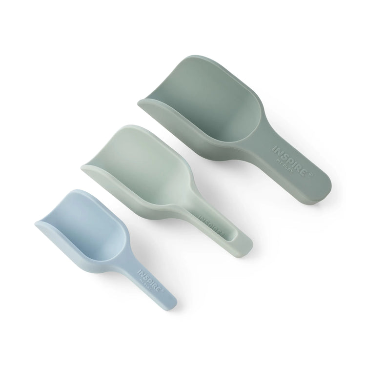 Three silicone sensory play nesting scoops in light blue, mint green, and sage green, arranged diagonally on a clean white background. The brand name 'INSPIRE MY PLAY' is embossed on the handles.