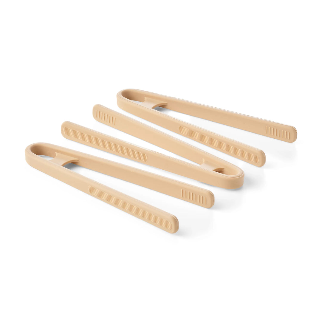 Three pairs of silicone sensory play tongs in natural beige shades, arranged diagonally on a white background.