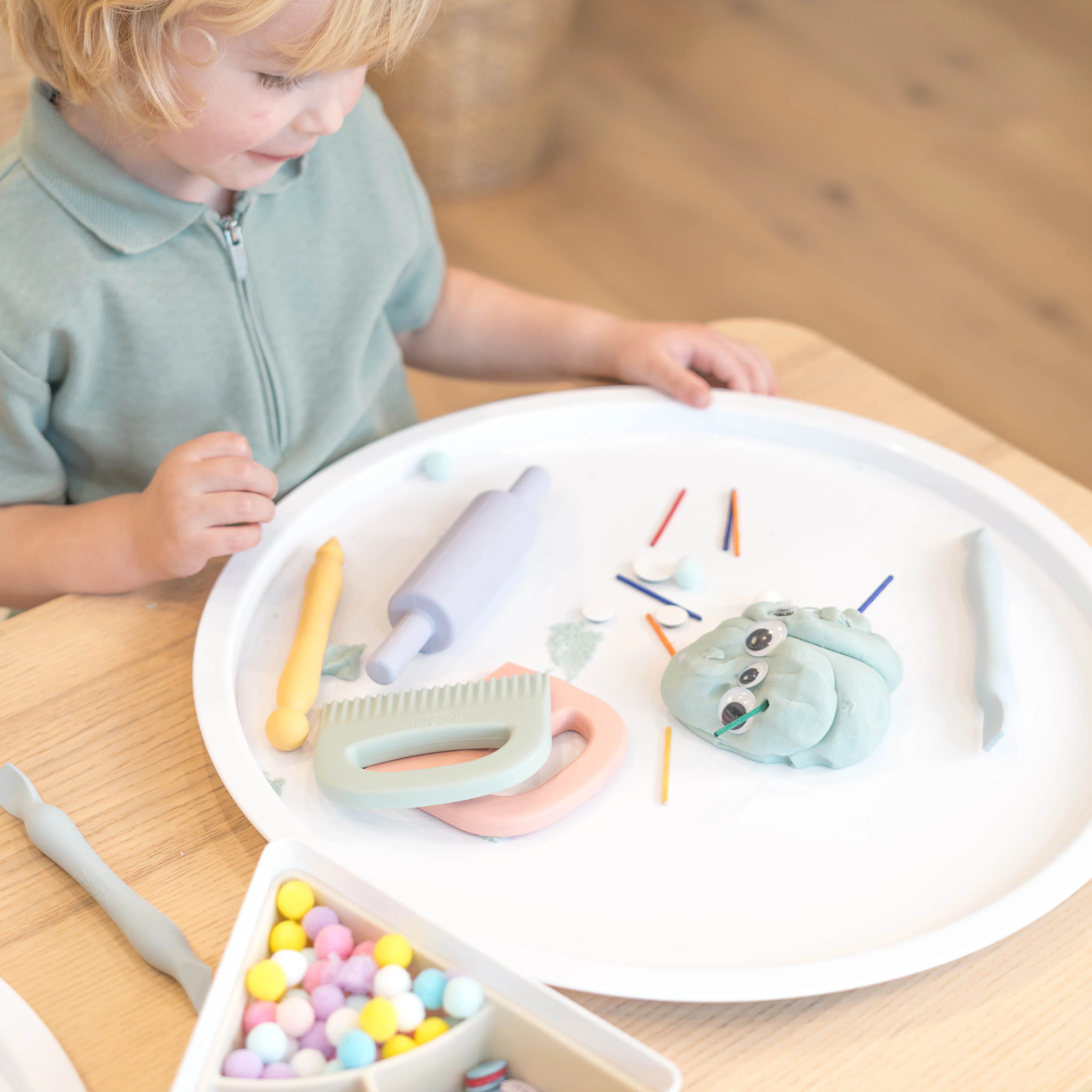Child playing with a set of colourful play dough tools on the Inspire My Play PlayTRAY lid.
