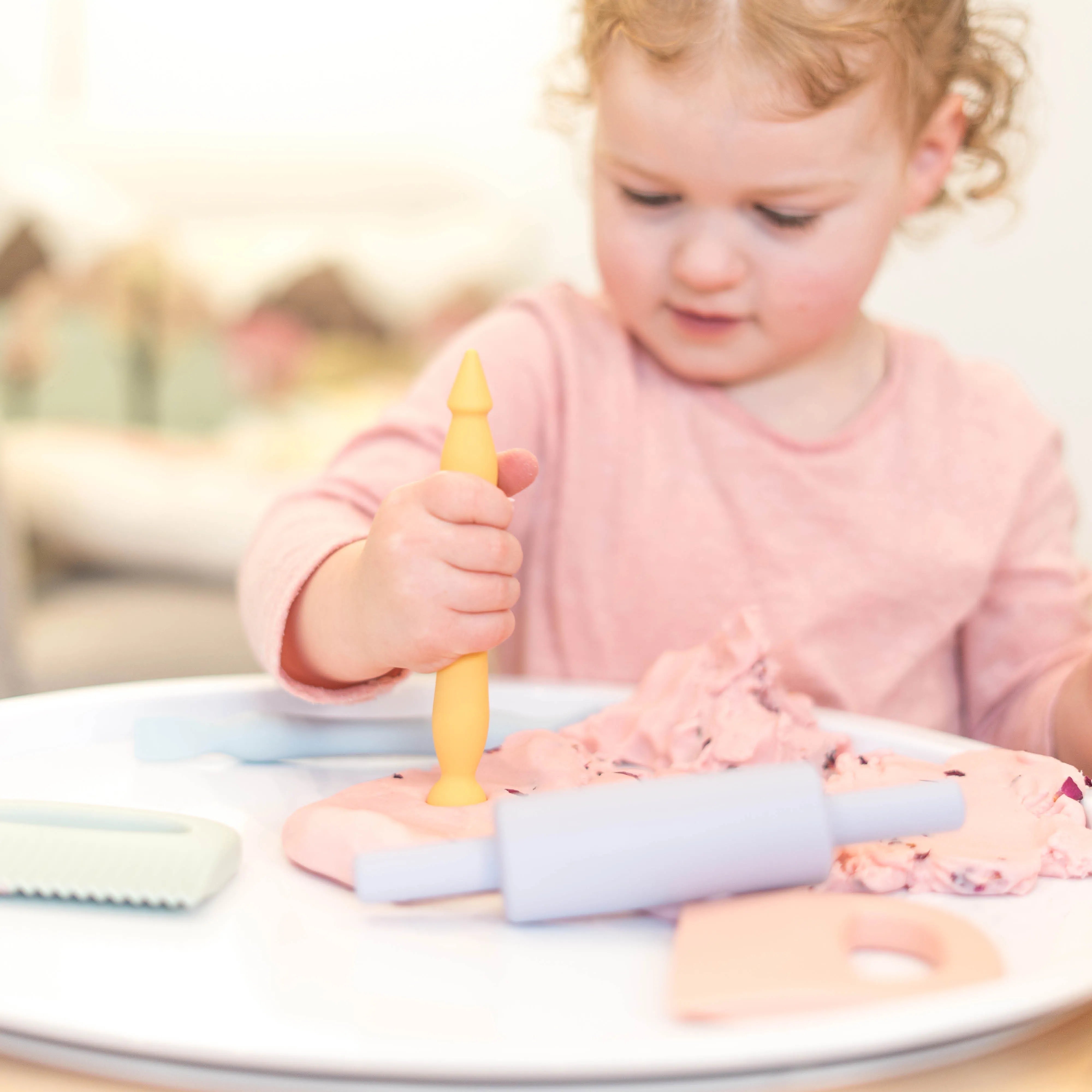 Child playing with play dough and playdough tools on the lid of the Inspire My Play PLlayTRAY.