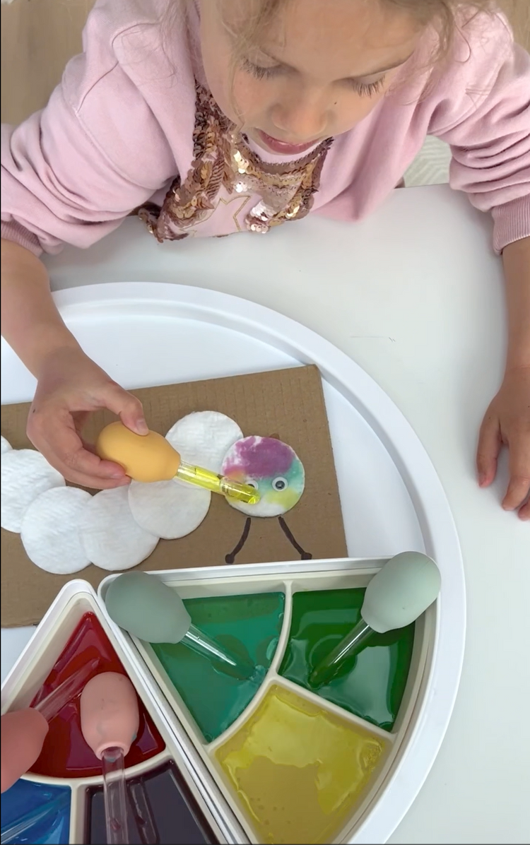 Child using sensory play droppers filled with coloured water to make a cotton wool caterpillar.